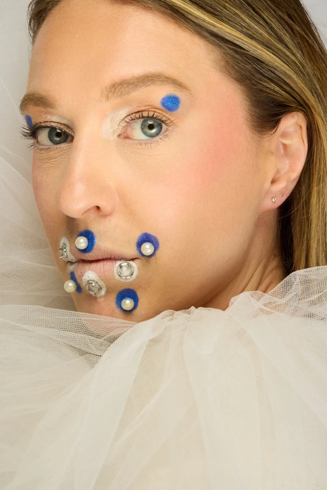 Perles et pompons bleus sur le visage, tulle blanc