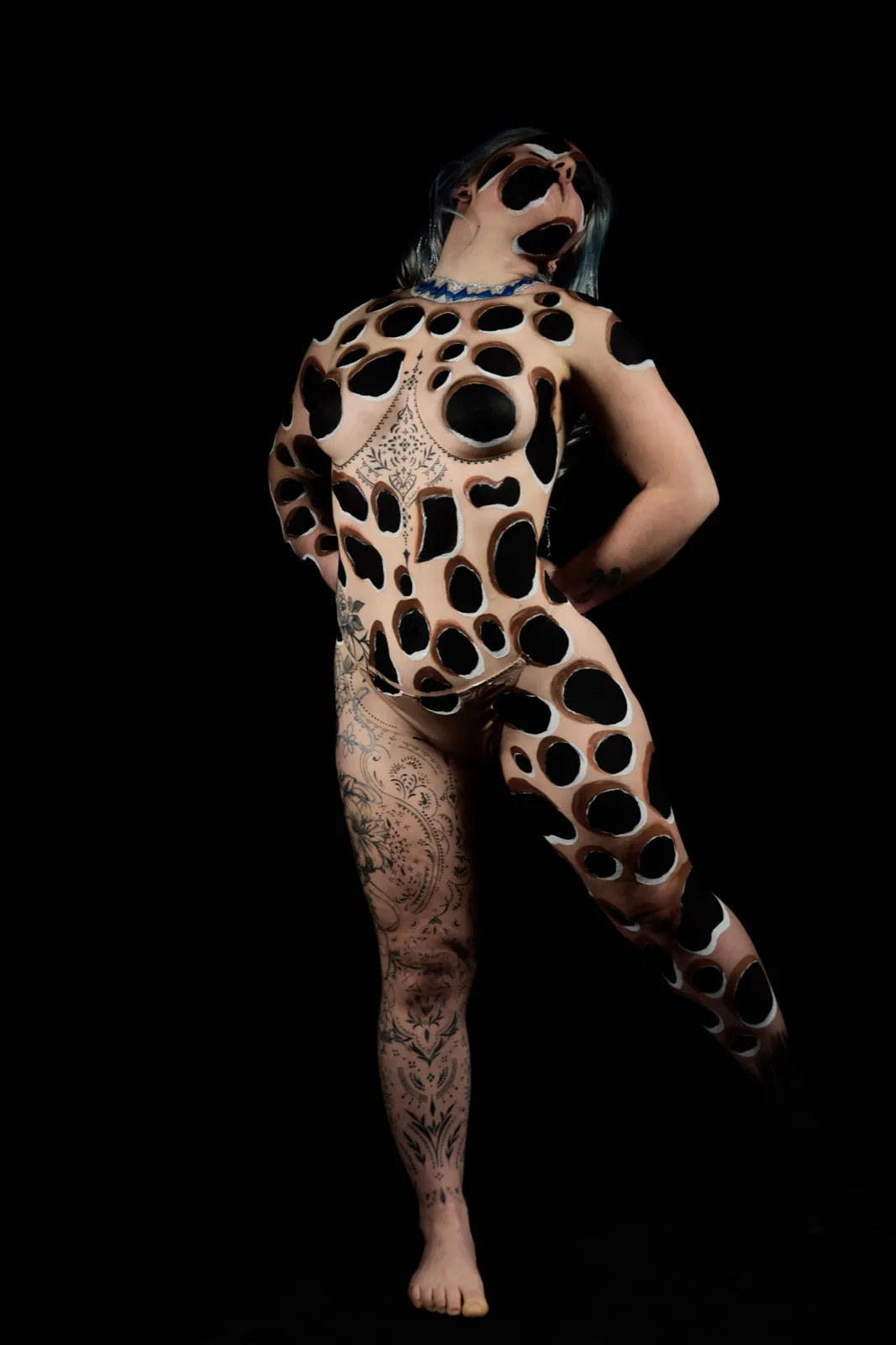 Body paint perforations en trompe-l'œil sur fond noir, pose debout